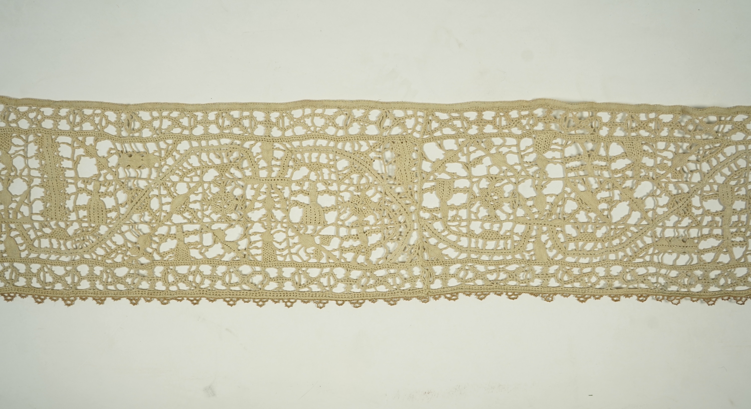 A length of late 16th early 17th century Venetian Reticella needle lace. Possibly cut from a wider panel or the edge to an Ecclesiastical robe or a furnishing lace. Designed with figures, worked in button hole stitch. 17